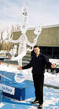 Man smiling next to a large stylized angel wings sculpture at an event