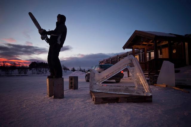 Silhouette of an ice sculptor working on a structure against a sunset sky