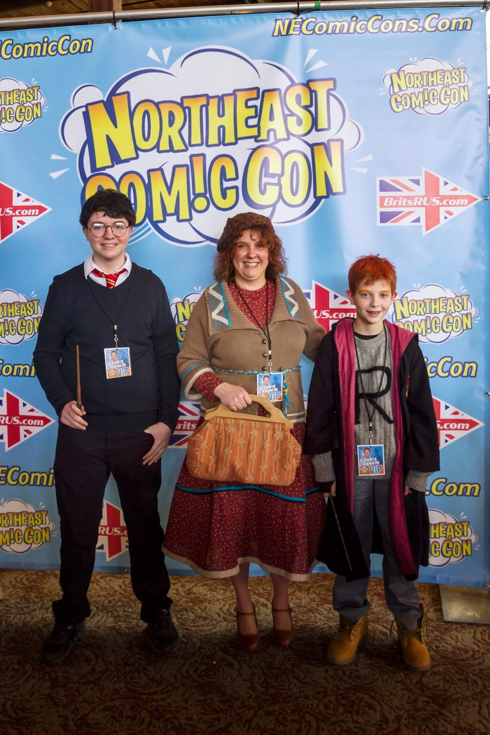 Three friends posing together in front of a colorful Northern Comic Con backdrop