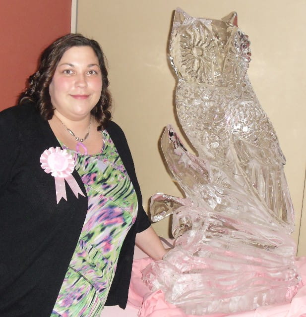 Woman standing beside owl ice sculpture