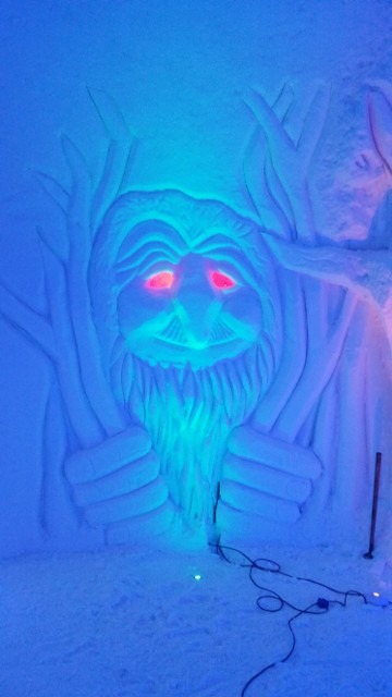 Intricate ice carving of a fierce mythical creature face with red eyes