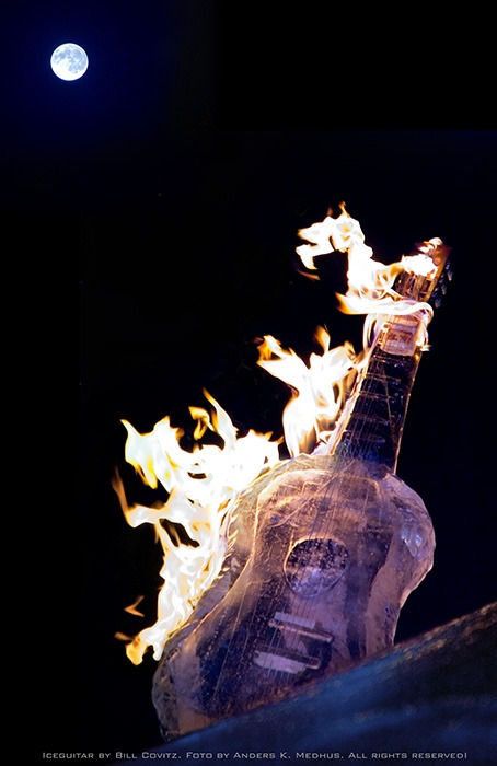 Dramatic ice sculpture display glowing with real fire torches at night