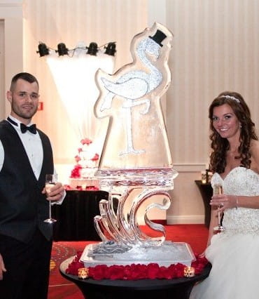 Bride and groom beside custom wedding ice sculpture