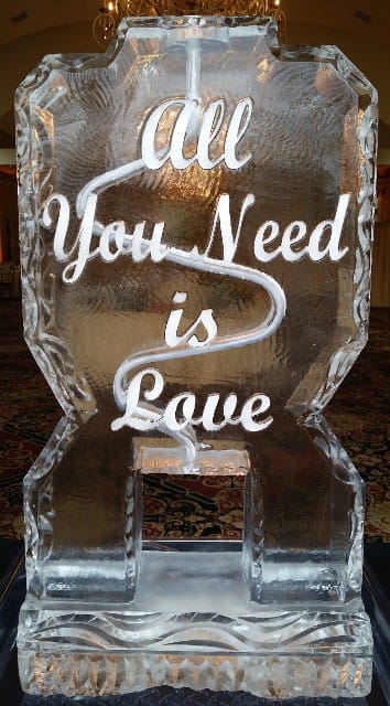 Engraved ice sculpture featuring the quote "You Need Is Love"