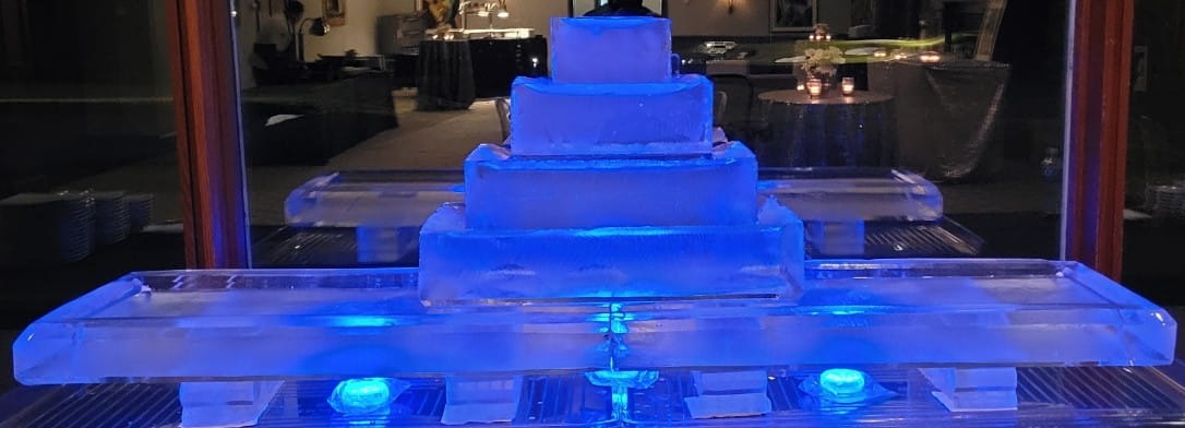 Multi-tier blue illuminated ice sculpture resembling a wedding cake display