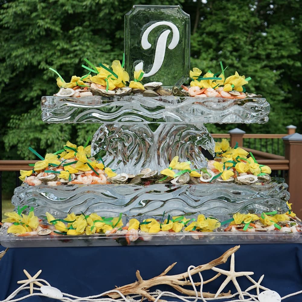 Custom ice sculpture with decorative letter P monogram and floral ice base