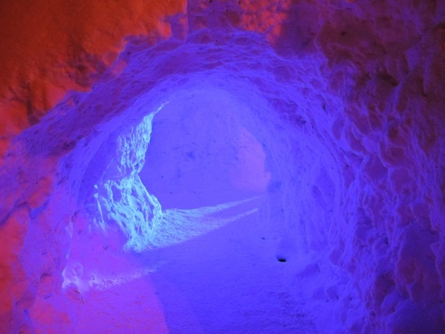 An entry archway tunnel opening leading inside a deep red and purple lit snow dome