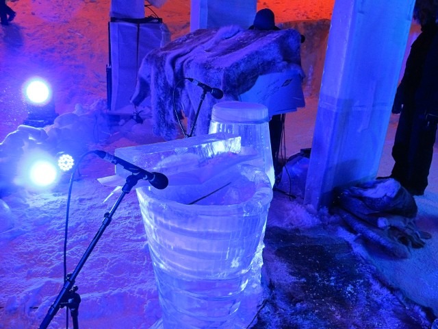 Audio mixing boards and studio gear set up inside a glowing blue ice cavern room