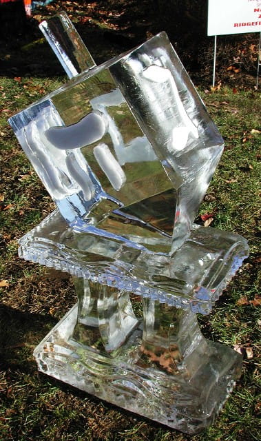 Abstract geometric clear ice carving resting on a grass surface