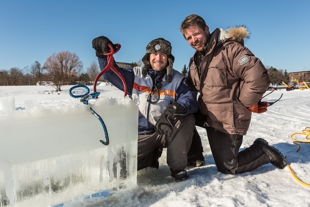Two festival crew members smiling together outdoors in heavy winter parkas