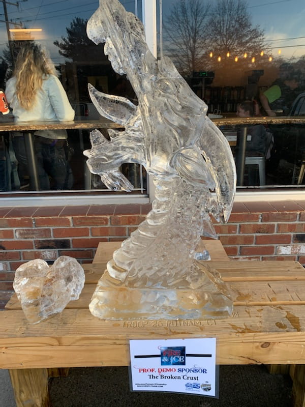 Intricate custom animal ice sculpture displayed outdoors on a brick patio