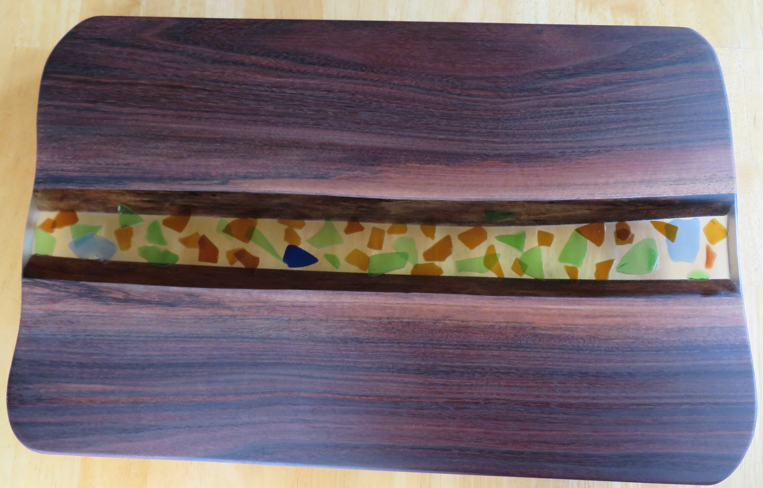 Handcrafted wooden serving board with a vibrant multi colored stripe inlay