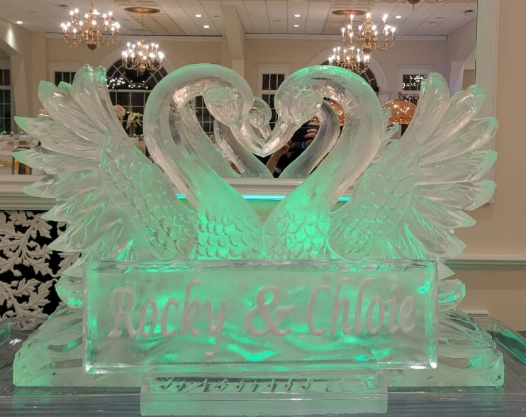 Double swan heart ice sculpture illuminated with soft green ambient lighting