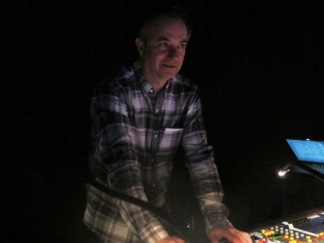 Man standing next to a dark background beside a clear ice block setup
