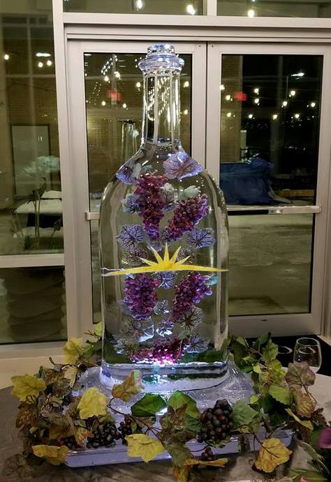 Custom liquor bottle ice luge sculpture featuring embedded purple grapes