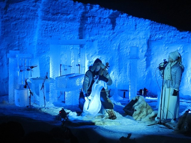 People gathering inside a completely furnished ice lounge hall lit in blue