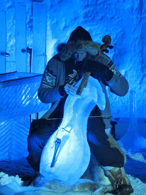 Musician playing a stringed instrument beside a detailed horse head ice sculpture