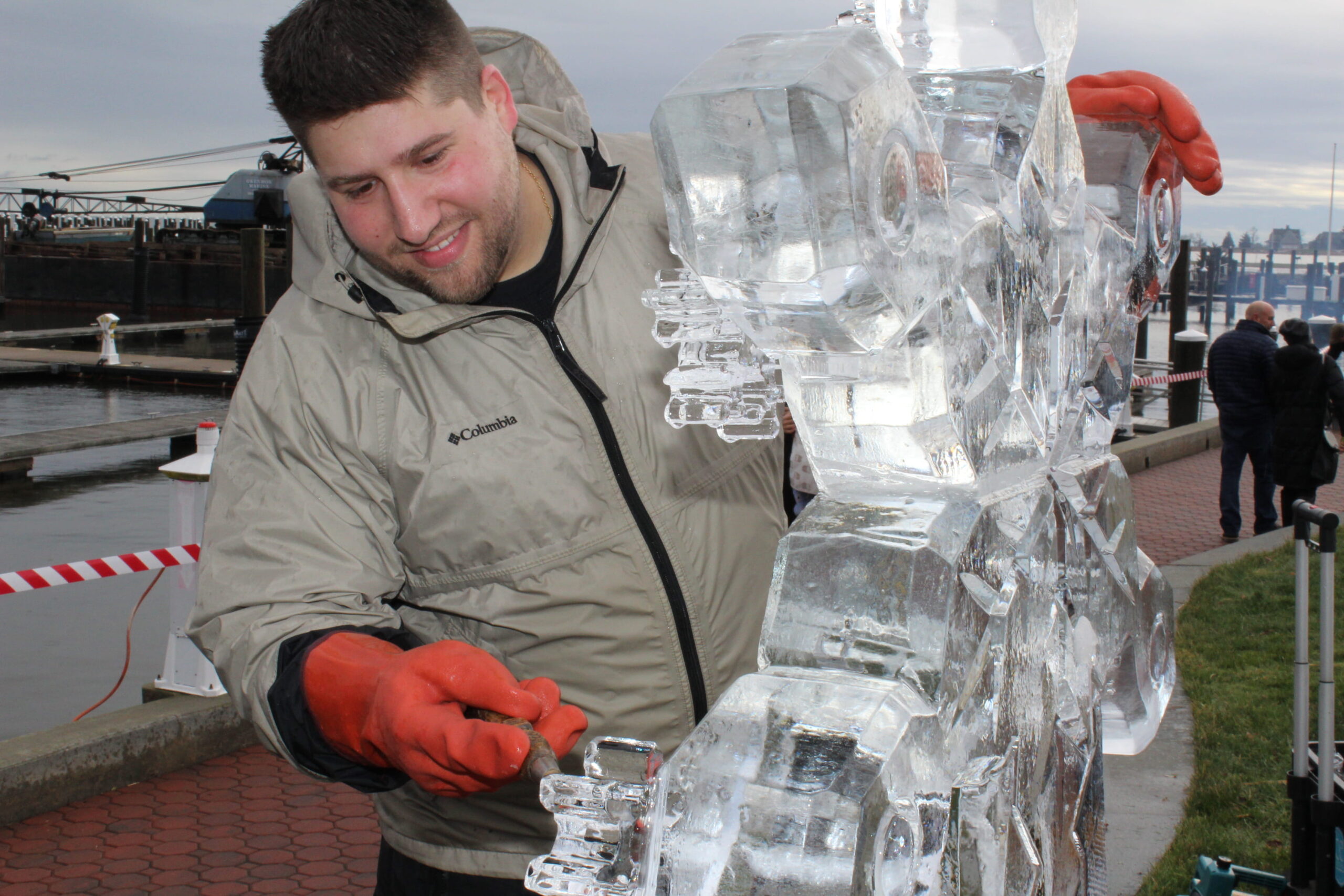 Smiling ice sculptor presenting a completed crystal clear ice carving outdoors