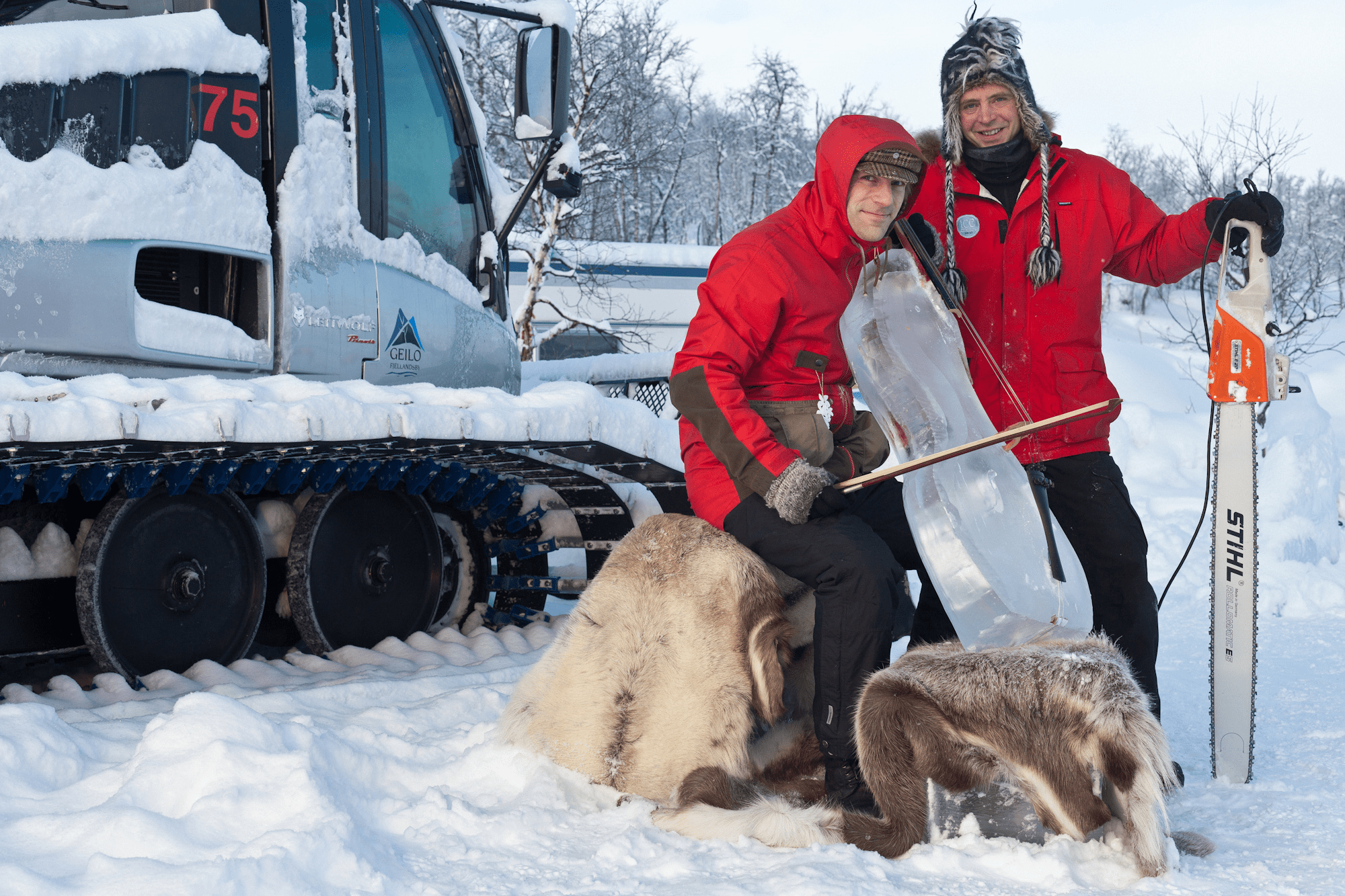 Two workers using heavy shovels near ice blocks at an outdoor winter festival site