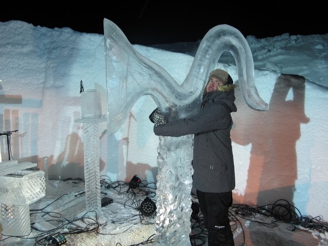 Artist polishing the smooth curves of a large public outdoor ice installation