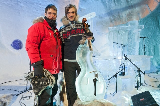 Two winter festival crew members standing proudly next to a completed ice sculpture