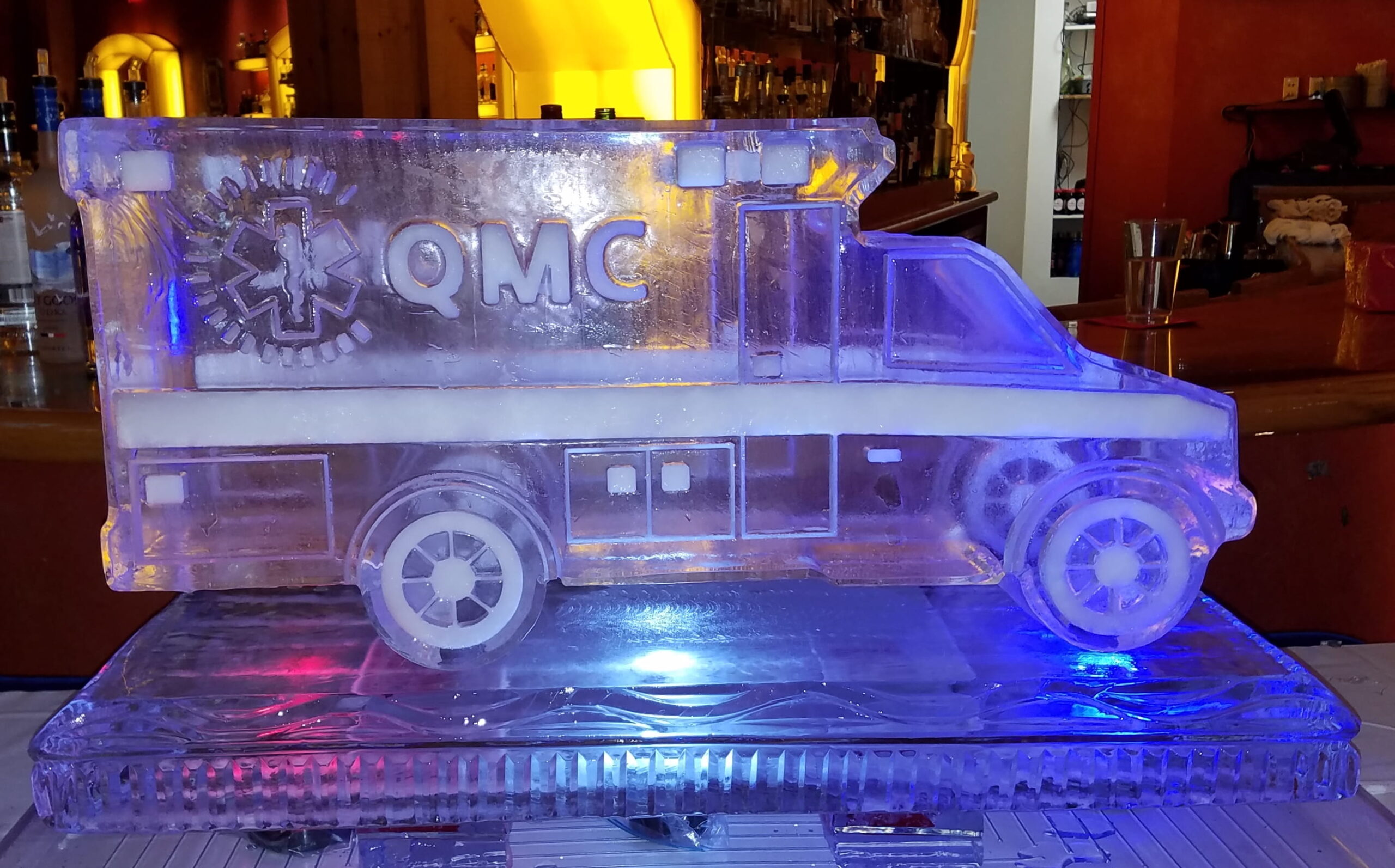 Detailed custom delivery truck ice carving illuminated with purple and orange lighting