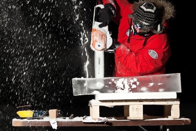 Close up of an artisan shaving and shaping a block of ice with a power tool