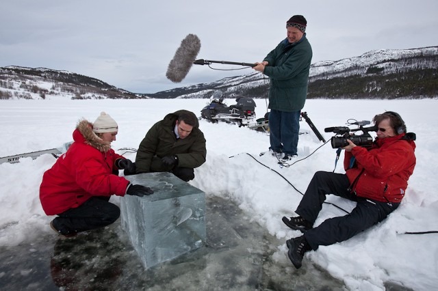 Production crew filming a documentary or video at a snowy ice festival site