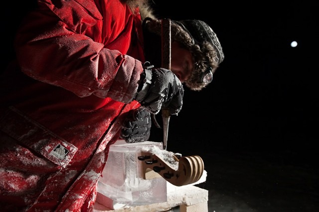 Close up of an artist meticulously chiseling a block of clear ice